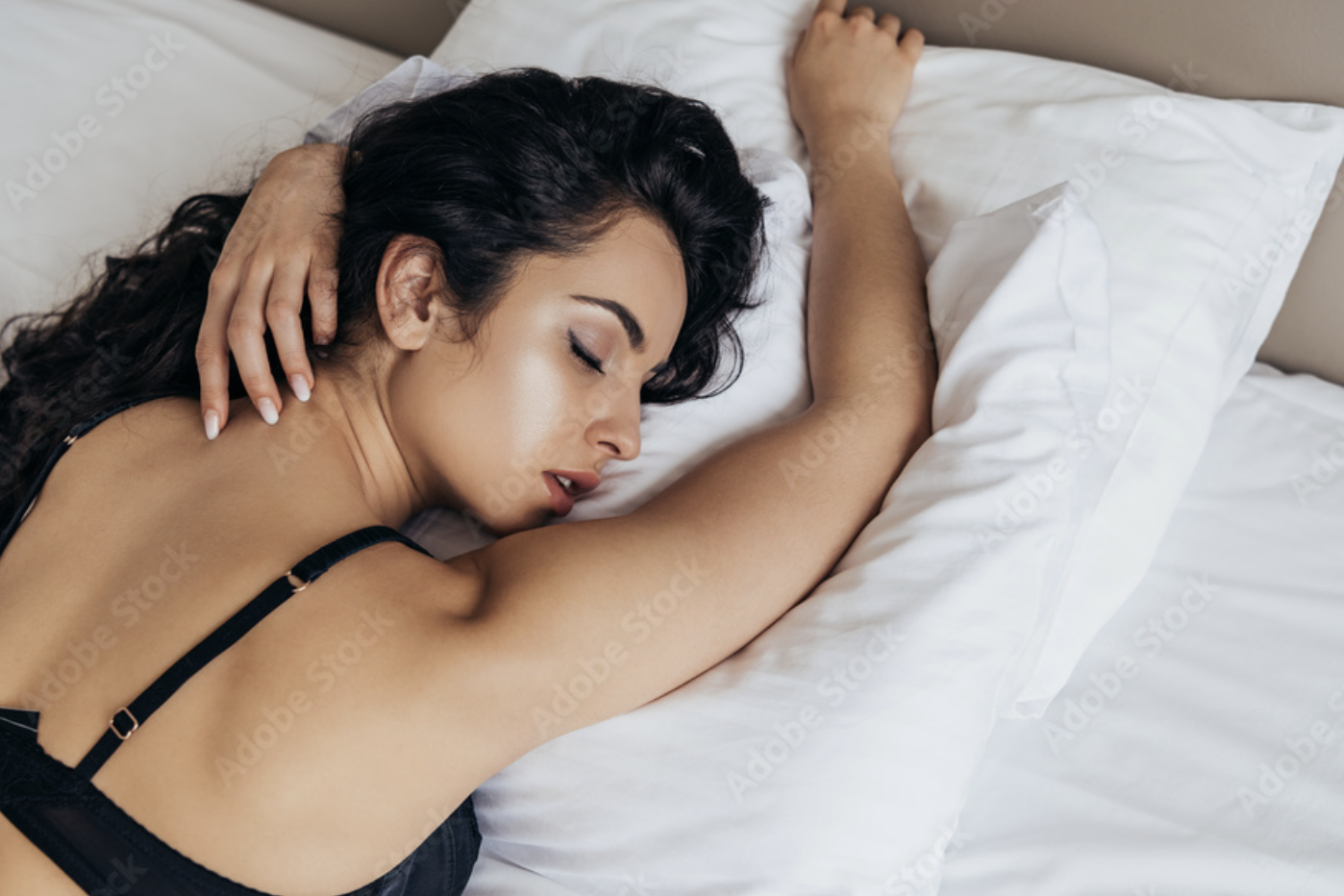 Vrouw liggen op haar buik op bed met kussen.