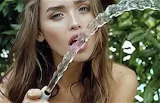 Vrouw die uit een tuinslang drinkt